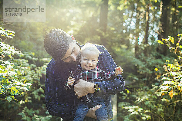 Vater hält seinen kleinen Sohn im Arm und liebt ihn im Freien.