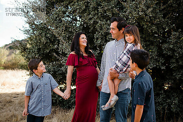 Schwangere Mutter lacht mit Familie im Feld in San Diego