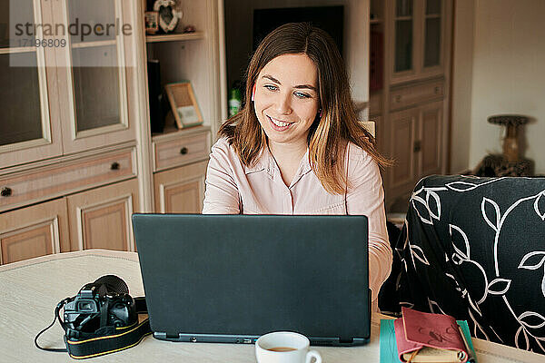 Junge Frau arbeitet von zu Hause aus an ihrem Laptop