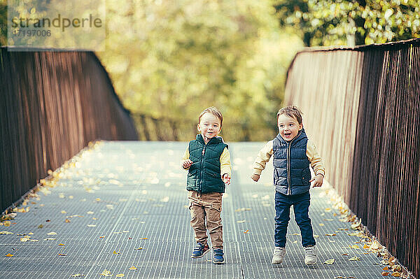 Adorable glücklich Zwillingsjungen mit Spaß und Springen im Herbst Natur