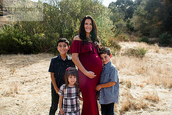 Schwangere Mutter posiert mit drei Kindern auf einem Feld in San Diego