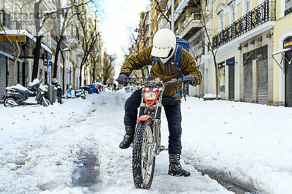 Porträt eines Mannes auf einem Motorrad auf der Straße im Winter