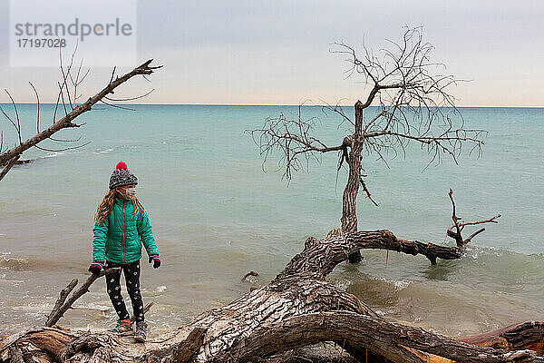 Seitenansicht eines Kindes  das bei kaltem Wetter am Seeufer spazieren geht