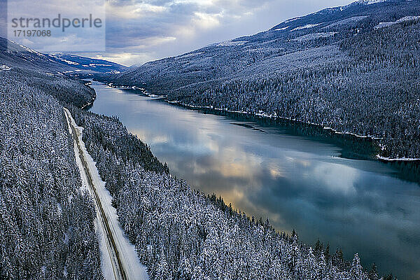 Idyllische Aufnahme eines Flusses inmitten von Bergen im Winter bei Sonnenuntergang