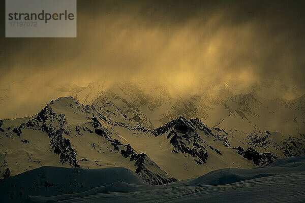 Landschaftlicher Blick auf schneebedeckten Berg gegen bewölkten Himmel bei Sonnenuntergang