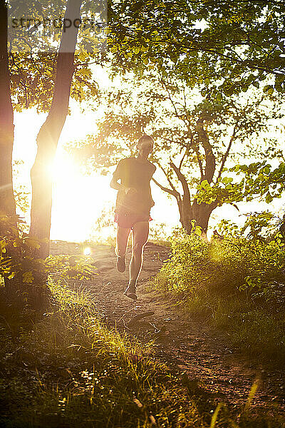 Erwachsener männlicher Trailrunner auf einem Bergkamm zur goldenen Stunde