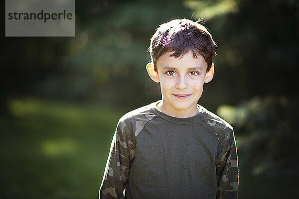 Süßer kleiner Junge im Tarnhemd mit großen braunen Augen im Freien.