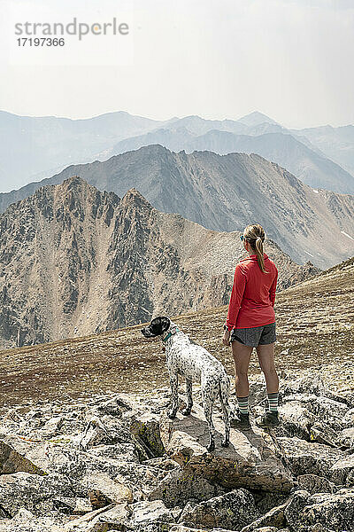 Rückansicht einer Wanderin mit Hund auf einem Berg gegen den Himmel im Urlaub