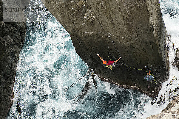 Ein Bergsteiger klettert in Tasmanien  Australien  auf einen Pfeiler aus dem Meer.