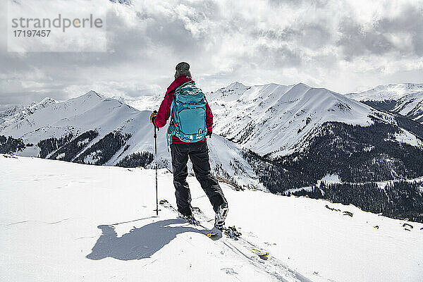 Rückansicht einer Frau mit Skiern auf einem schneebedeckten Berg gegen den Himmel im Urlaub