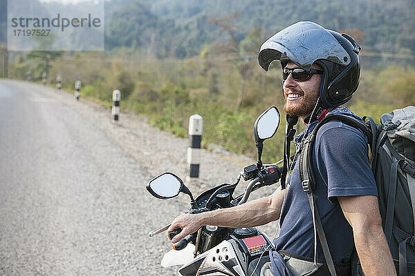 junger Mann auf einem Motorrad in Laos