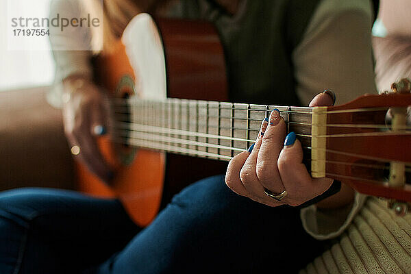 Nahaufnahme einer Frau mittleren Alters beim Gitarrenspiel. Musik lernen