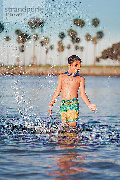 Junge  der im Sommer in der Bucht im Wasser plantscht.