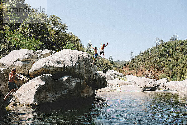 Drei Jungen springen gleichzeitig in ein kalifornisches Schwimmloch.