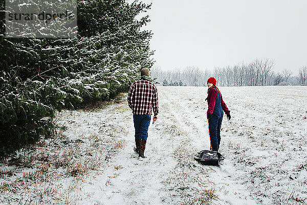 Zwei Teenager gehen durch ein verschneites Feld mit Kiefern in Michigan