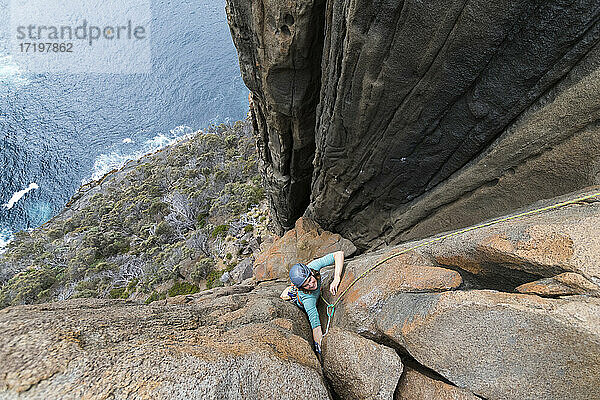 Eine Abenteurerin und Bergsteigerin klettert die Doleritklippen von Cape Raoul  Tasmanien  Australien  hinauf.