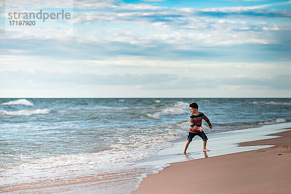 Junge am Michigansee  der sich am Strand im Wasser vergnügt