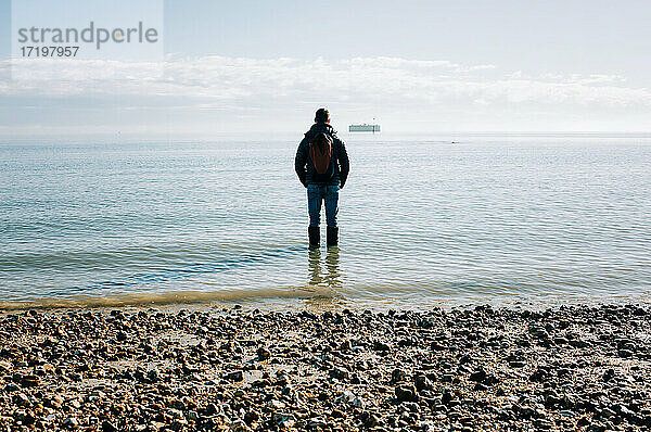 Ein Mann stand im Meer und dachte nach  betrachtete und träumte in der Sonne