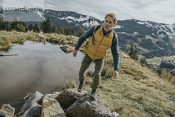 Älterer Mann beim Wandern auf einem Felsen im Salzburger Land  Österreich