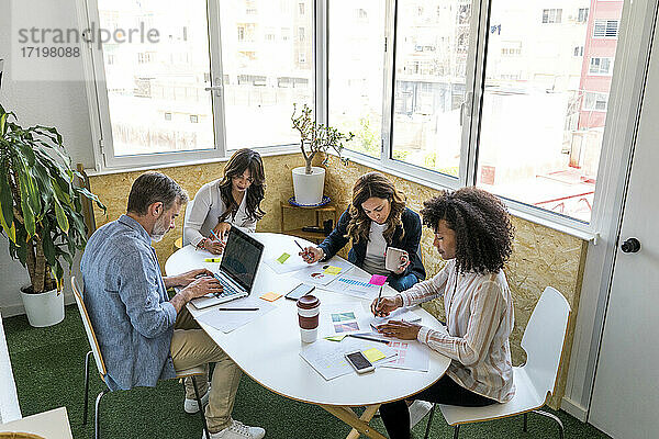 Männliche und weibliche Kollegen sitzen bei der Arbeit im Büro am Tisch