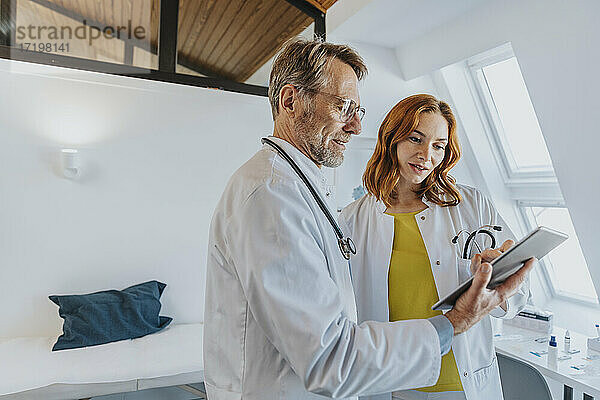 Männlicher Mitarbeiter arbeitet mit einem Arzt über ein digitales Tablet in einer Klinik