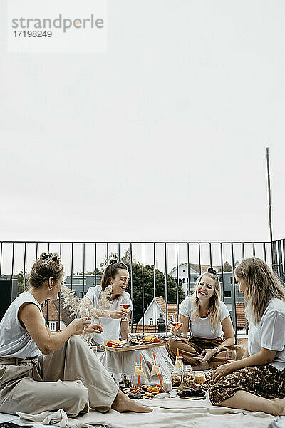 Freunde genießen ein ausgiebiges Picknick auf der Dachterrasse