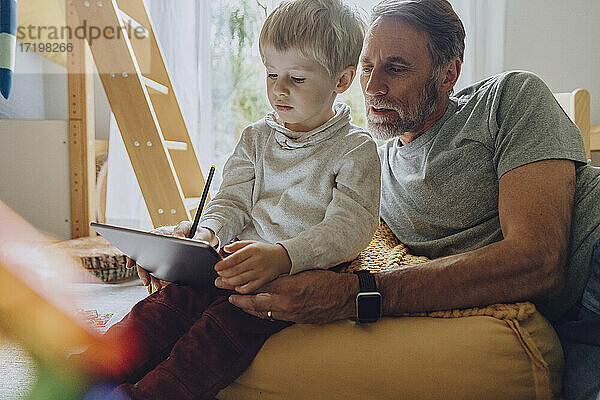 Vater sucht Sohn  der einen digitalen Tablet-Computer im Schlafzimmer benutzt