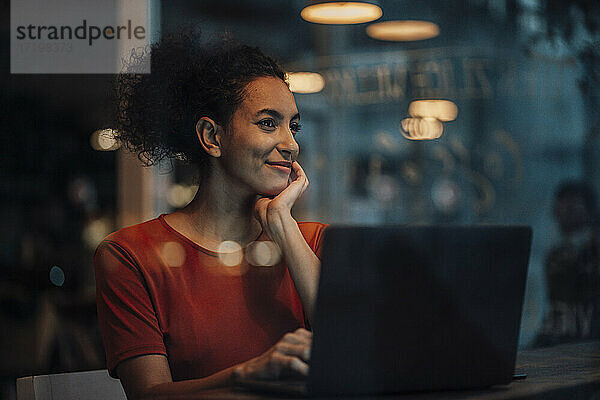 Nachdenkliche Frau mit Laptop  die wegschaut  während sie im Café sitzt