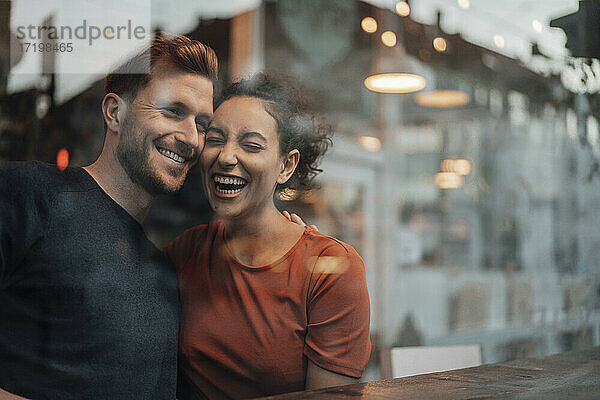 Glückliches Paar  das lachend am Tisch eines Cafés sitzt