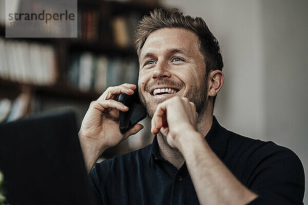 Mid erwachsenen Geschäftsmann lächelnd während des Gesprächs auf dem Handy sitzen im Café