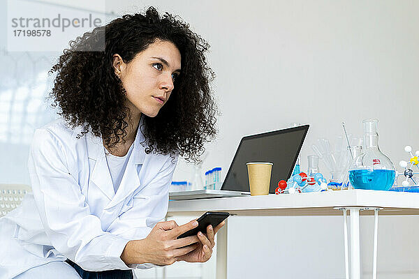 Nachdenkliche Ärztin mit Smartphone  die in der Klinik wegschaut