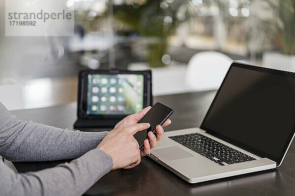 Geschäftsmann die Hände mit Smartphone durch Laptop im Büro