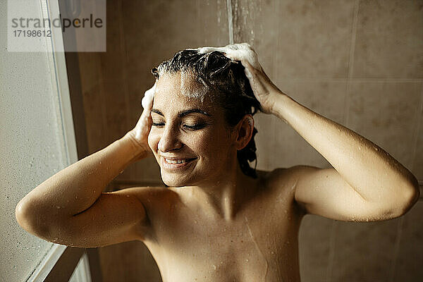 Porträt einer erwachsenen Frau  die unter der Dusche lächelt