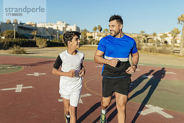 Lächelnder Vater sieht seinen Sohn beim Laufen auf dem Sportplatz an