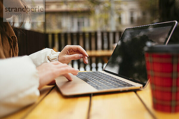 Frau benutzt Laptop in einem Straßencafé