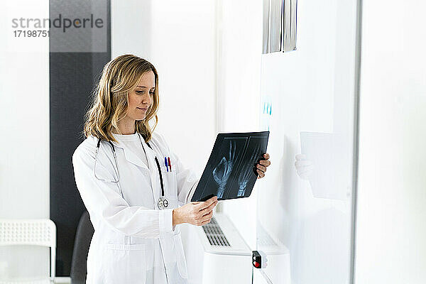 Blonde Radiologin bei der Untersuchung von Röntgenbildern in einer medizinischen Klinik