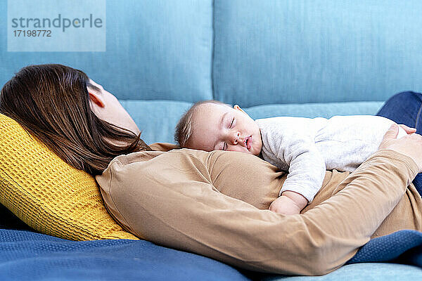 Mutter mit Sohn schlafend auf Sofa im Wohnzimmer zu Hause