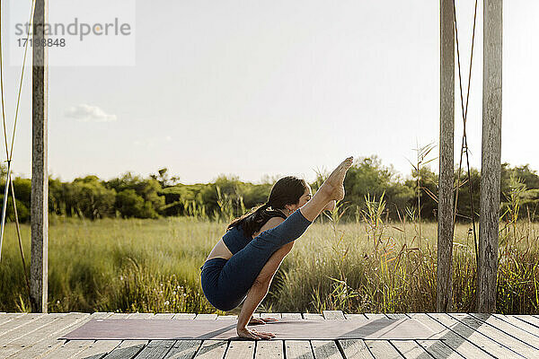 Starke Frau macht Tittibhasana Yoga-Pose am Pavillon