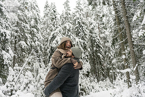 Junger Mann  der eine Frau auf dem Arm trägt  während er im Wald steht