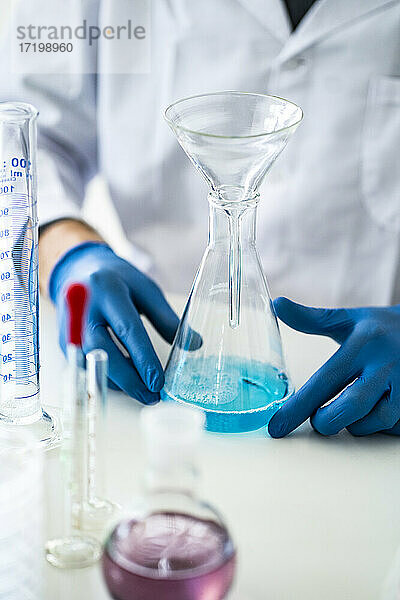 Wissenschaftler hält Chemiekolben mit Trichter im Labor