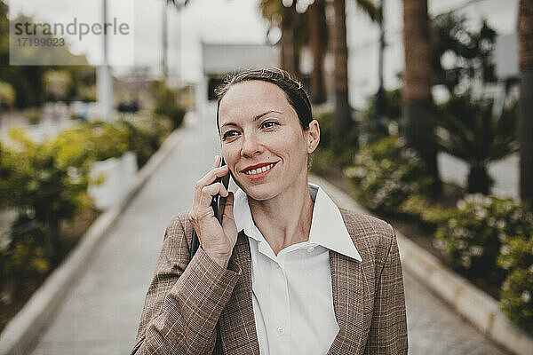 Lächelnde Unternehmerin  die am Telefon spricht und wegschaut