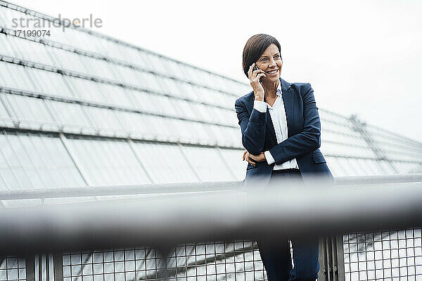 Weibliche Unternehmerin spricht mit einem Smartphone vor einem Bürogebäude