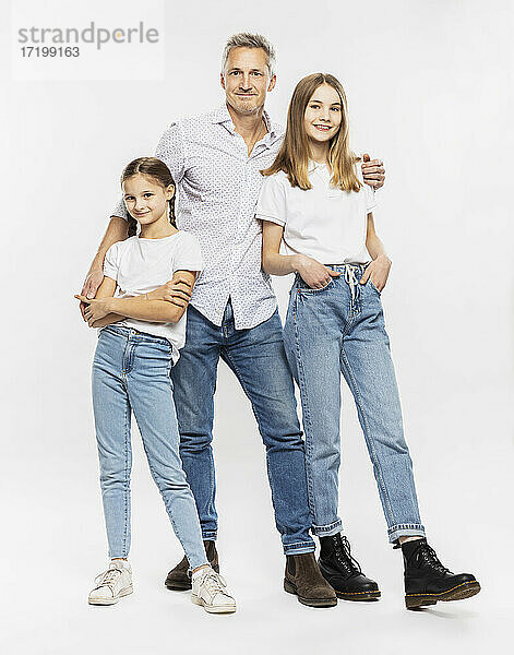 Vater und Töchter stehen zusammen vor weißem Hintergrund