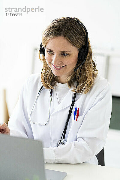 Lächelnde Ärztin bei der Online-Konsultation über einen Laptop in einer medizinischen Klinik