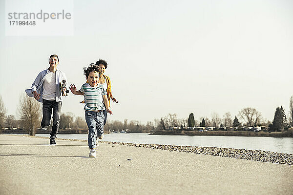 Glücklicher Sohn läuft mit Eltern im Hintergrund auf der Straße