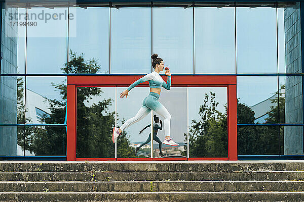 Aktive Sportlerin beim Laufen auf den Stufen an der Glaswand