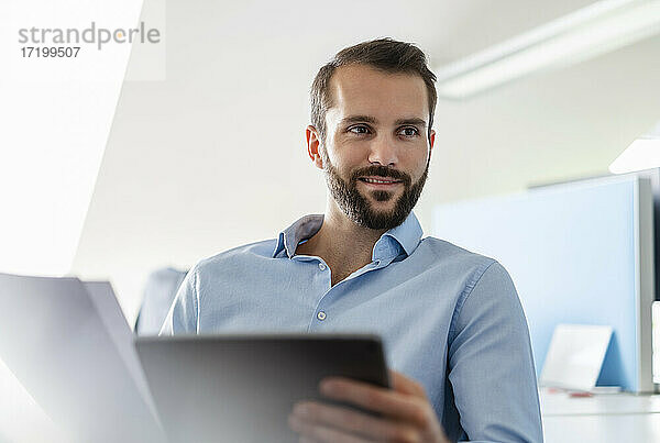 Geschäftsmann mit Papier und digitalen Tablette lächelnd im Büro