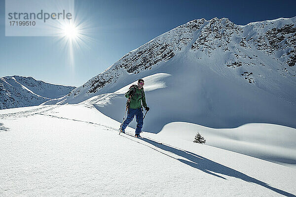 Mann beim Skitourengehen auf der schneebedeckten Steinkarspitze  Lechtaler Alpen  Tirol  Österreich