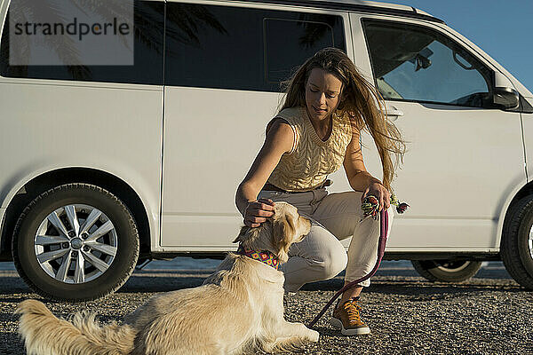 Frau streichelt am Wochenende ihren Hund am Wohnmobil