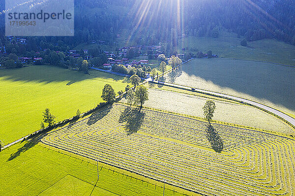 Deutschland  Bayern  Bayrischzell  Drohnenansicht eines grünen Bergfeldes mit Dorf im Hintergrund